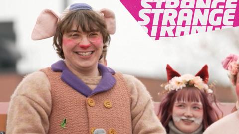 A man in a pig costume and the Strange logo