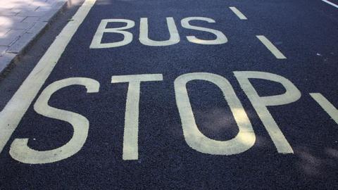 A sign painted on an asphalt road saying 'bus stop' in yellow