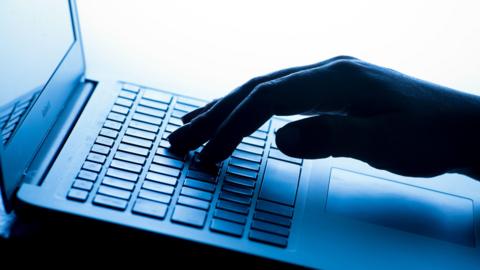 A close up of a hand typing on a laptop keyboard.