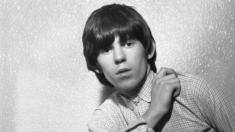 Black-and-white photo of Keith Richards wearing a checked shirt in 1964
