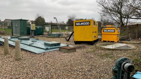 A gravelled area with tanks, pipes and pumps across the site