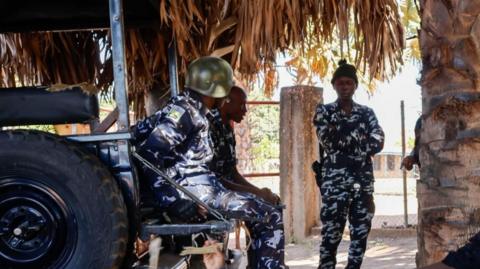 Three police officers are seen outside the school from where children were abducted in Papiri village in Nigeria's Niger state