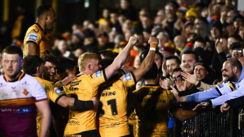 Castleford players come together with try scorer Tom Weaver to celebrate with fans behind the in-goal area