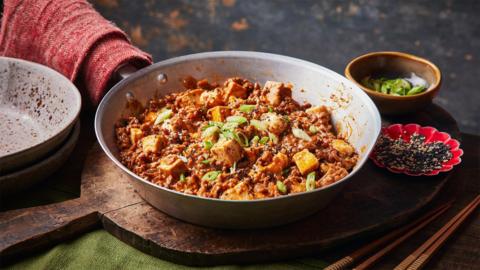 Image of Korean-style mapo tofu, served in a white dish on a wooden chopping board