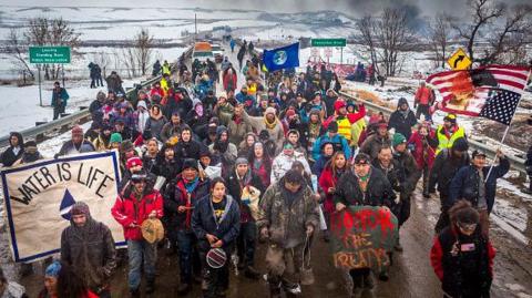 Protesters wearing colourful clothing and holding signs in the barren North Dakota snow