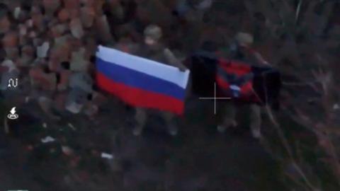 A soldier holds up a Russian flag in Kurakhove, Donetsk Region, Ukraine in this screen grab taken from a social media video released on 5 January