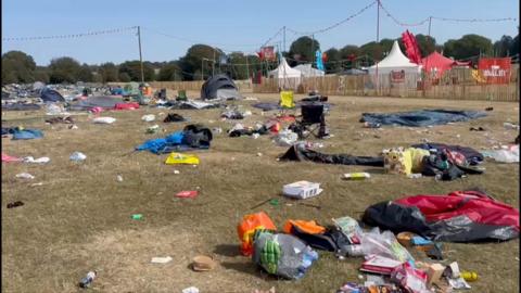 Tents along with litter shown strewn on a grassy field