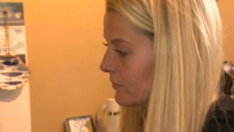 A close-up of Laura Muller - a woman with long, straight, blonde hair, waiting for her coffee maker to finish in her kitchen.