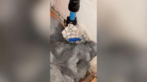 A pipe pouring water and a tea towel around it.