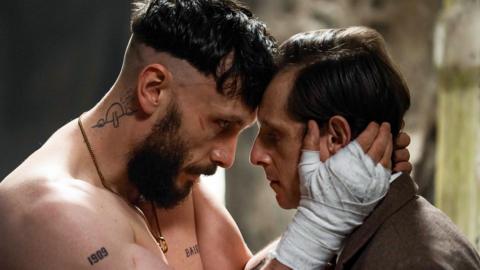 This image shows a very close, tightly framed scene featuring two people facing each other at extremely close range, with their foreheads nearly touching.