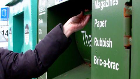 Person putting recycling into a recycling bin.
