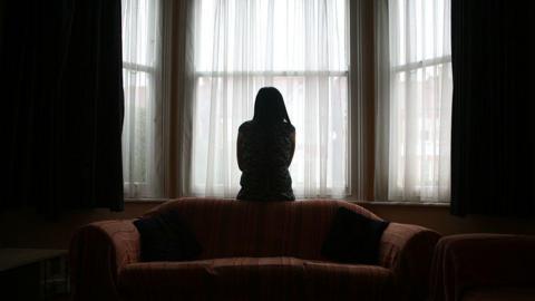 A woman in a darkened room. 