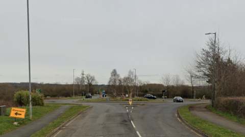 The A6003 Stamford Road after a collision at the roundabout with Burley Park Way