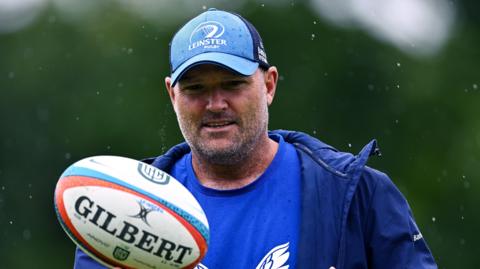 Jacques Nienaber holds a rugby ball during a Leinster training session