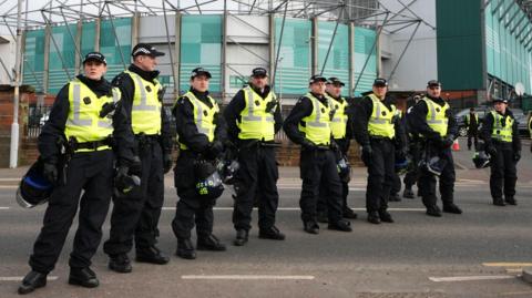 A row of police officers wearing hi-viz vests lined up outside Celtic Park