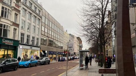 A generic shot of Belfast city centre, royal avenue area... Rows of shops with cars parked on pavements