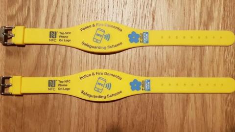 Two yellow wristbands with the words "police and fire dementia safeguarding scheme" on them