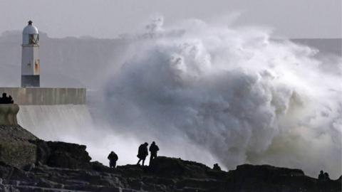 Silhouette of people viewing large waves near lighthouse as Storm Eowyn arrives, in Porthcawl, Wales, Britain, January 24, 2025. 