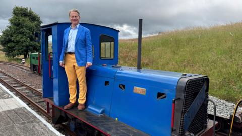 Michael Portillo standing on a train