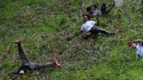 Men falling down the hill - once has his legs in the air and IShowSpeed is sliding down with mud on him