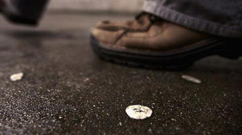 Chewing gum on street with man's shoes in background.
