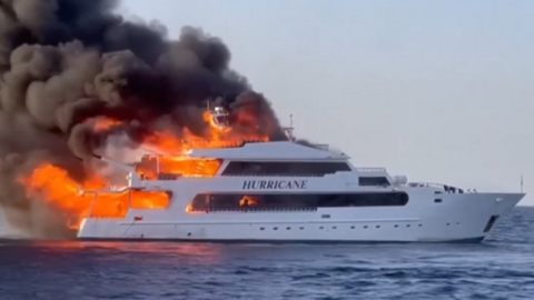 A large boat with "Hurricane" written on the side. There is a large fire coming from the back of the boat.
