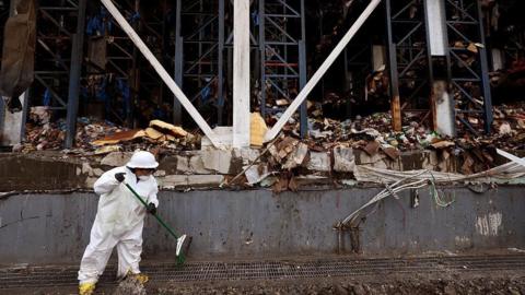 A worker helps clean up the site of the massive Lineage warehouse fire along Union Pacific Avenue in the Boyle Heights on June 30, 2026. Signal Restoration Services is a national emergency cleanup and property damage firm. The stench from millions of pounds of rotting food spread through the neighborhood and city officials and neighborhood residents look to hold those responsible for the fire and its aftermath accountable. Lineage has begun the colossal task of removing an estimated 85 million pounds of spoiled food from the facility