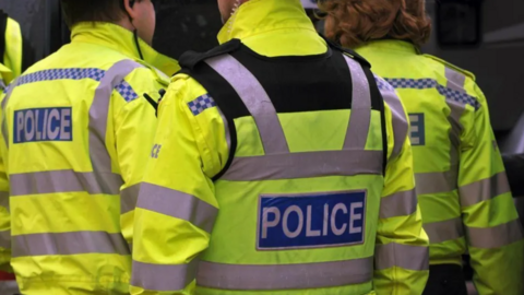 pic of the back of police officers in their high visibility green uniform 