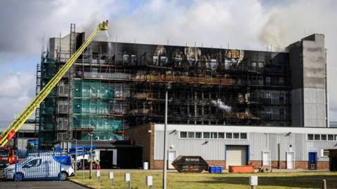 Building in east London is burned on the exterior, with blackened walls and still smoking.