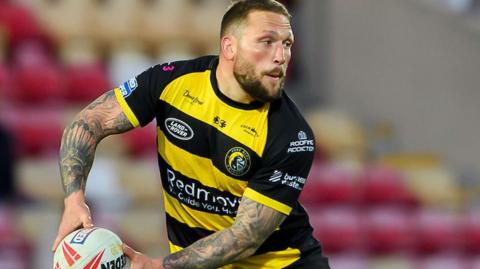 York Knights player Josh Griffin, in yellow and black, about to pass the ball