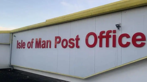 A wide shot of the Isle of Man Post Office sign. It is all written in red letters.