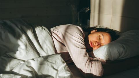 Woman sleeps off on weekends. Tired woman naps under bright sunlight after restless night. - stock photo
