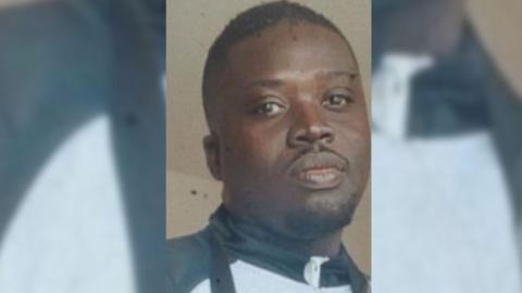 Godrick Osei looks at the camera, he is wearing a sports jacket with a high neck. 
