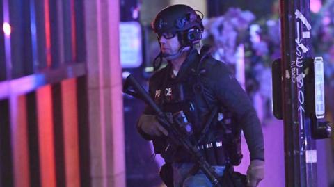 An armed policeman searching for a suspected gunman