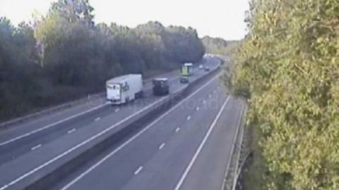 Grainy CCTV camera still shows a few cars and lorries heading away from the camera but empty lanes in the opposite direction on the motorway.
