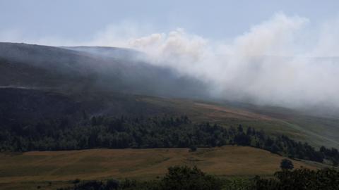 Smoke from a moorland fire rises near the Dovestone Reservoir in Manchester.
