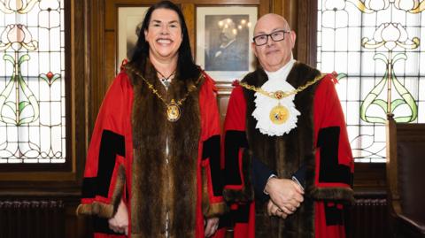 Kewin and Crellin in red and black ceremonial robes and wearing the mayoral chains in the Douglas Council chamber.