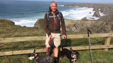 Man stood on a hillside with his two dogs