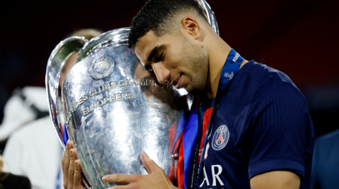 Paris St-Germain's Achraf Hakimi hugs the Champions League trophy after his side's 5-0 win over Inter Milan in the 2025 final in Munich
