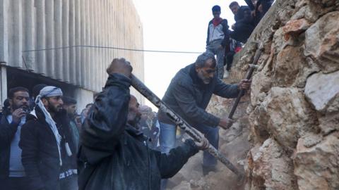 People chip away at a wall at Sednaya Prison on 9 December 2024 in Damascus, Syria