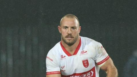 Karl Lawton carrying the ball in both hands but slightly towards his left-hand side playing for Hull KR