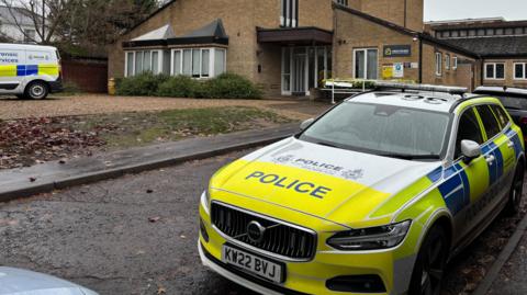A police car is parked on Somerleyton Street in Norwich. It is parked in front of Somerleyton House, an accommodation block. To the left of the picture is a white police forensics van.