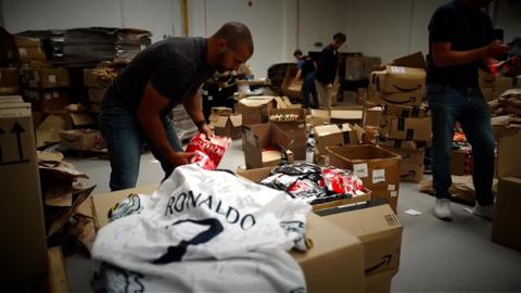 Officers from the Police Intellectual Property Crime Unit sorting through boxes of counterfeit football strips which they have seized as part of a crackdown on fakes throughout the world cup.