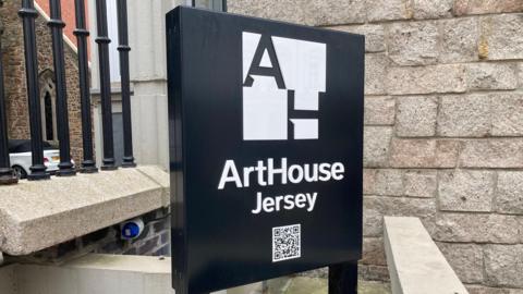An ArtHouse Jersey sign on a black background. It has a QR code under the text. 