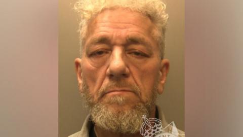 Antonio Villafane's mugshot. He has a beard and is not smiling while looking at the camera against a grey background.