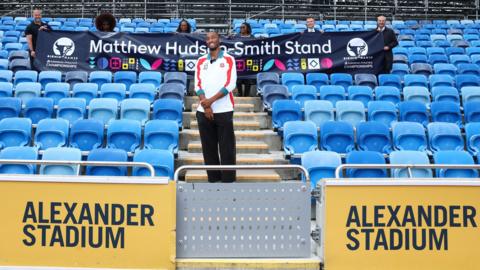 Matthew Hudson-Smith poses at Alexander Stadium in front of a banner reading "Matthew Hudson-Smith Stand"