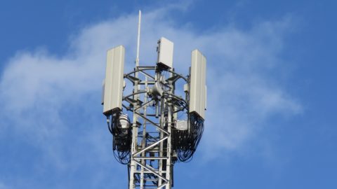 A mobile phone mast with various dishes and antenna against a blue sky