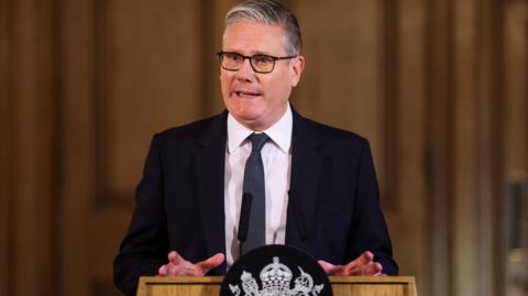 Prime Minister Sir Keir Starmer speaks in front of a podium at the start of a summit at Downing Street.
