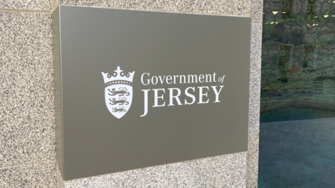 A picture of the from the front of the Government of Jersey building. There is a small sign which reads Government of Jersey in white.