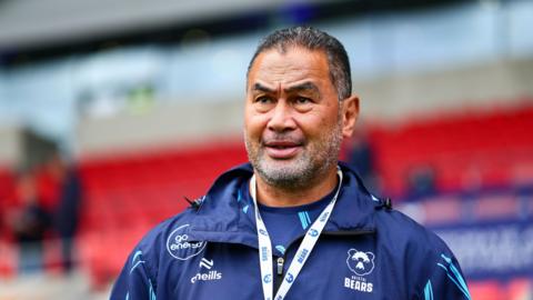 Pat Lam wearing a navy blue Bristol Bears jacket with a Bristol Bears lanyard around his neck ahead of their game at Sale's CorpAcq Stadium